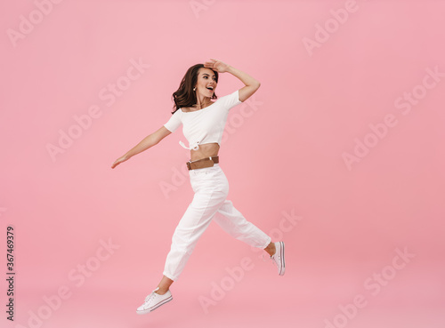 Image of delighted brunette woman walking and looking backward