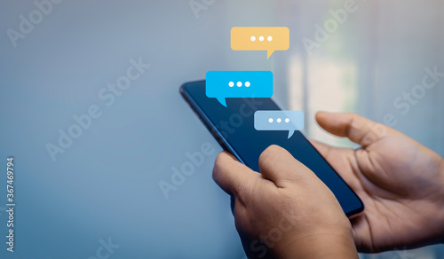 Person hand use smartphone typing, chatting conversation in chat bubble pop-up. Social media maketing concept.