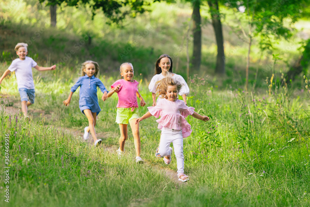 Kids, children running on meadow in summer's sunlight. Look happy, cheerful with sincere bright emotions. Cute caucasian boys and girls. Concept of childhood, happiness, movement, family and summer. Kids, children running on meadow in summer's sunlight. Look happy, cheerful with sincere bright emotions. Cute caucasian boys and girls. Concept of childhood, happiness, movement, family and summer.