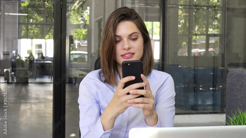 Funny euphoric young woman texting message on smartphone at modern office. Excited girl receive read good news on cellphone. Funny euphoric young woman texting message on smartphone at modern office. Excited girl receive read good news on cellphone.