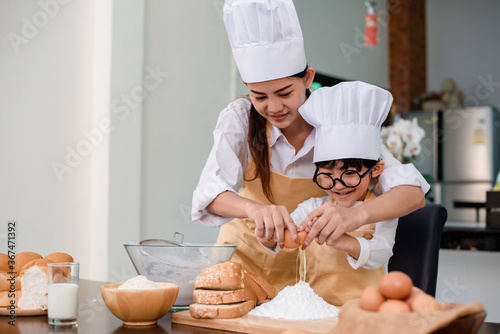 Mom teaching son for cooking food. Mother and kid daily lifestyle at home. Asian family together in the kitchen. photo