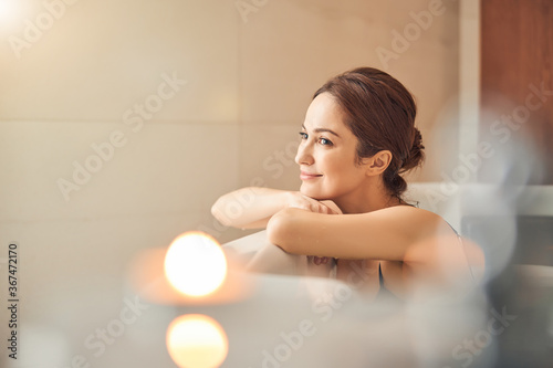 Smiling lady daydreaming in a hydromassage bath photo