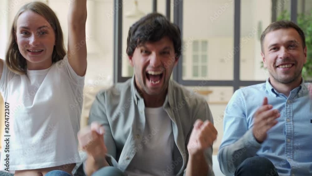 Funny friends celebrate the victory of their favorite team sitting on the couch Funny friends celebrate the victory of their favorite team sitting on the couch