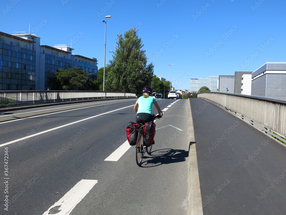 jeune femme cycliste à bicyclette avec sacoche pour randonnée à vélo sur  piste cyclable le long de la Loire et en Bretagne foto de Stock | Adobe  Stock