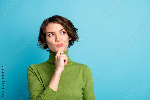 Portrait of minded interested girl touch finger chin look copyspace think thoughts decide decision wear green jumper isolated over blue color background photo