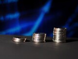 Pile of coins isolated on blue chart blurred background. Growth up to profit concept investment. Saving money, business and finance concept. Coin steps with light flare on blurred background