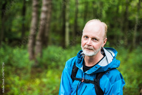 A portrait of a happy middle aged man hiking outside in the nature