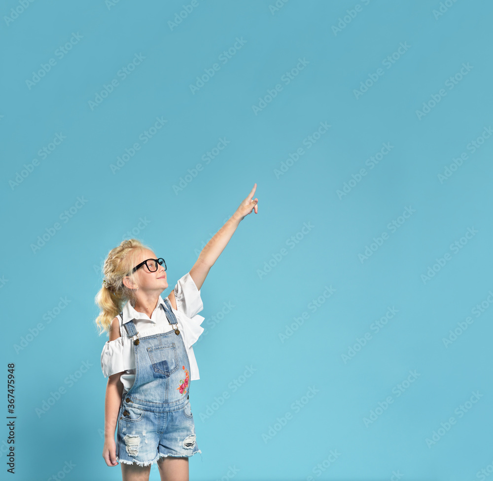 Cute little girl child 7 years old, points to the free space with a thumb up Cute little girl child 7 years old, points to the free space with a thumb up
