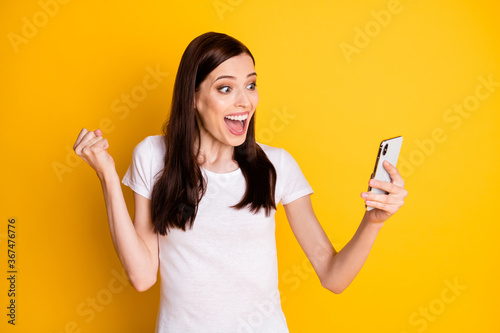 Portrait of her she attractive lucky cheerful cheery brown-haired girl using cell browsing good news like winning notification 5g app isolated on bright vivid shine vibrant yellow color background