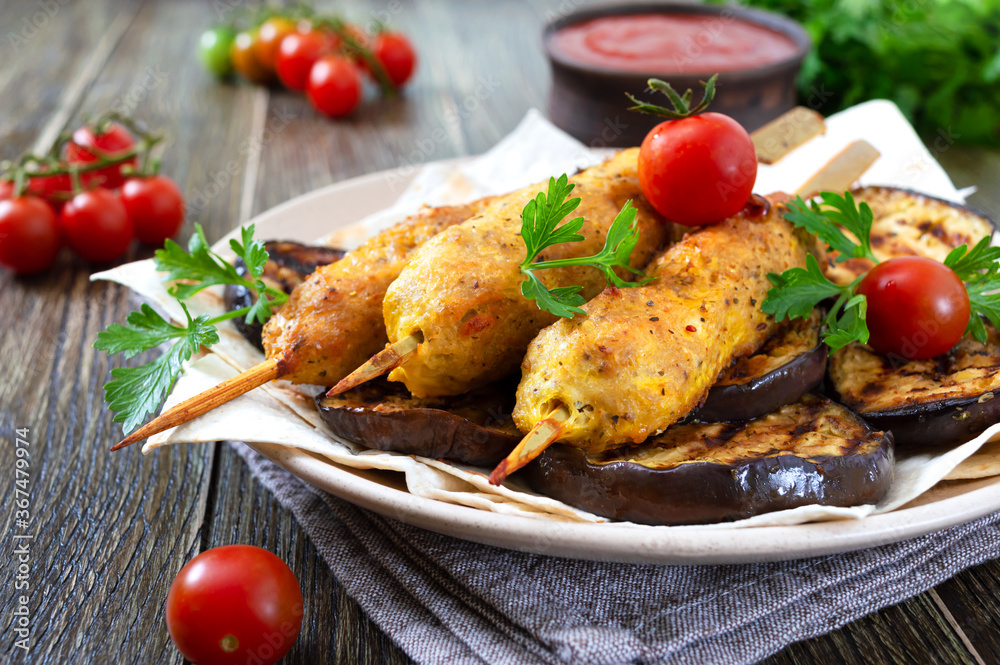 Lula kebab with grilled eggplant on pita bread. Dietary chicken kebabs on a skewer with vegetables. Lula kebab with grilled eggplant on pita bread. Dietary chicken kebabs on a skewer with vegetables.