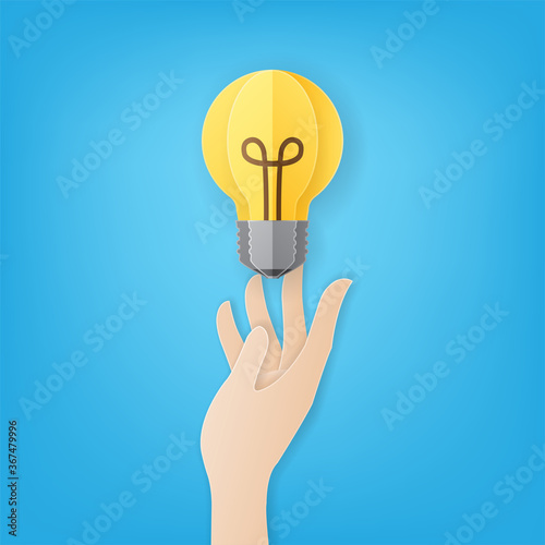 Paper art style of hand carrying light bulb on blue background