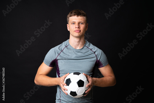 Handsome young football player man over isolated black wall © luismolinero
