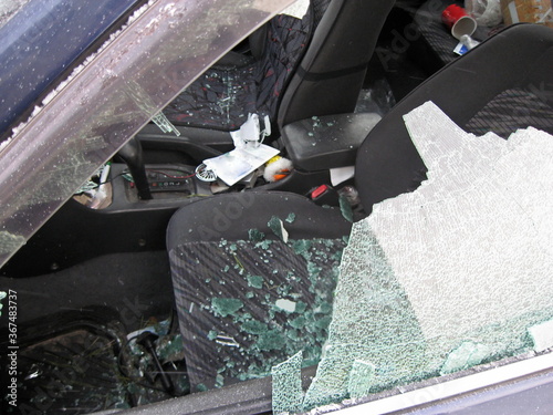 A broken window with splinters scattered across the interior of the car during a road accident close-up. blurred focus