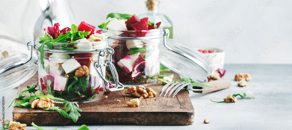Beet salad with arugula, goat cheese and nuts, trendy salad jar, gray kitchen table. Panoramic banner with copy space - obrazy, fototapety, plakaty 