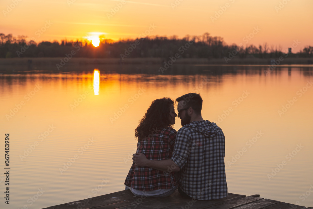 Couple kissing at lake docks, enjoying the sunset
