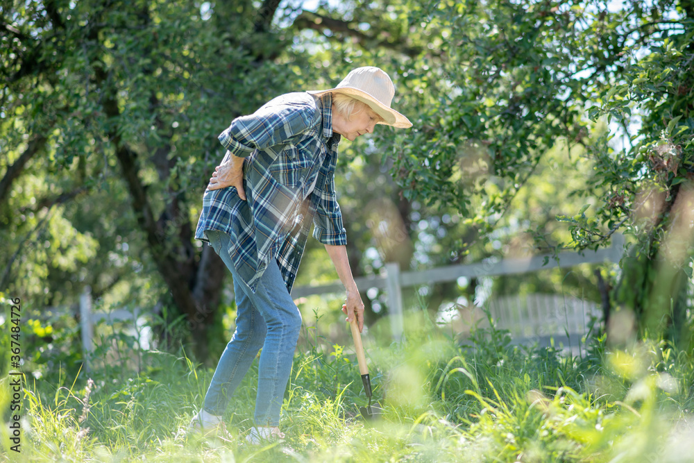 Woman having problems with gardening because of backache Woman having problems with gardening because of backache