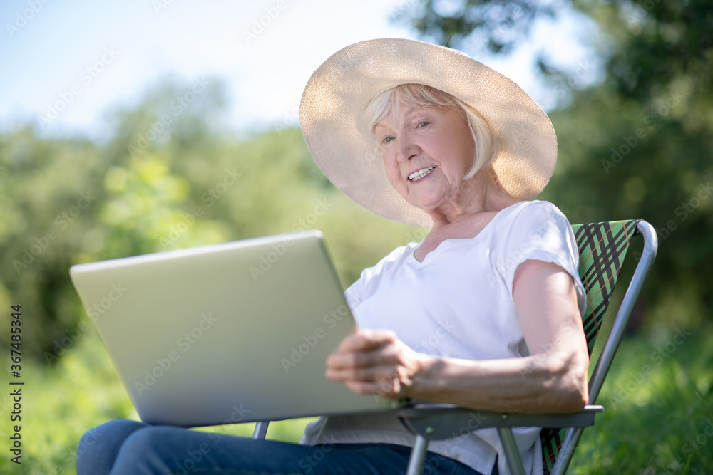 Fototapeta premium Elderly woman working with the computer outdoor