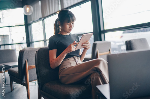 Attractive asian businesswoman using tablet at city cafe. Drinking coffee and surfing the internet and read news. social distancing concept.