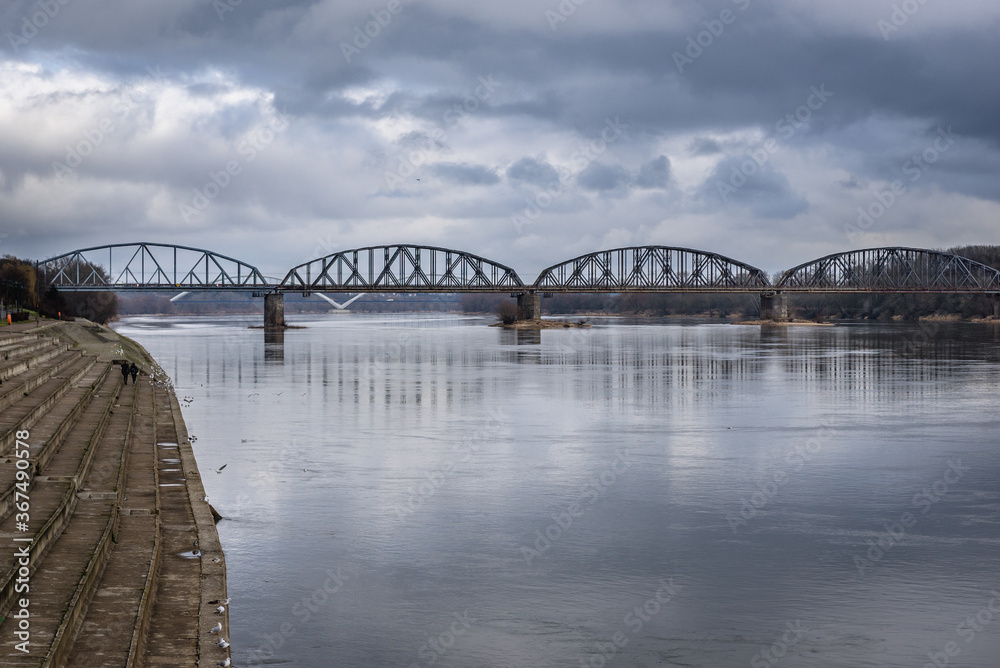 Naklejka premium Railway bridge over River Vistula, viewfrom embankment near old town of Torun city in north central Poland