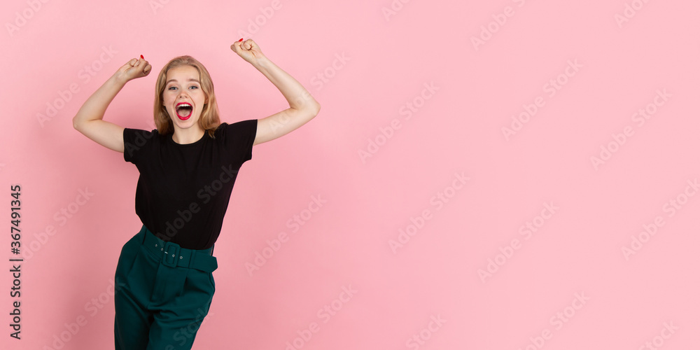 Celebrating. Portrait of young emotional woman gesturing on pink studio background. Human emotions, facial expression, sales, ad concept. Blonde caucasian pretty model gesturing. Copyspace. Flyer.