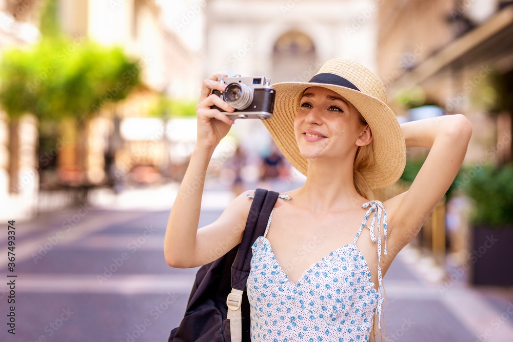 Portrait shot of young female tourist using vintage camera to taking photos in the city.