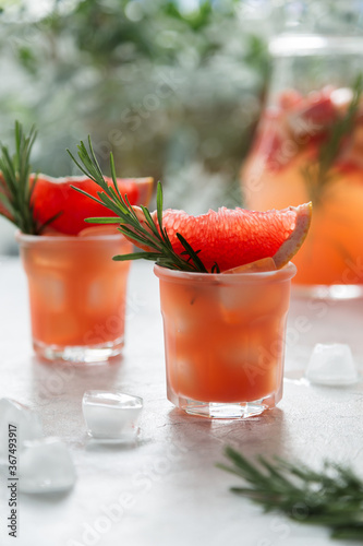 Grapefruit lemonade. Two cold wet drinking glasses with fresh grapefruit nonalcohol beverage. Ice, rosemary. photo