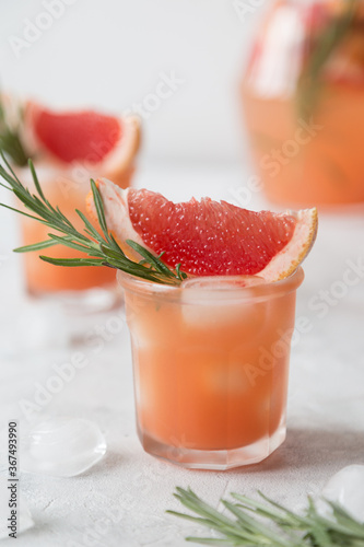 Grapefruit lemonade. Two cold wet drinking glasses with fresh grapefruit nonalcohol beverage. Ice, rosemary.