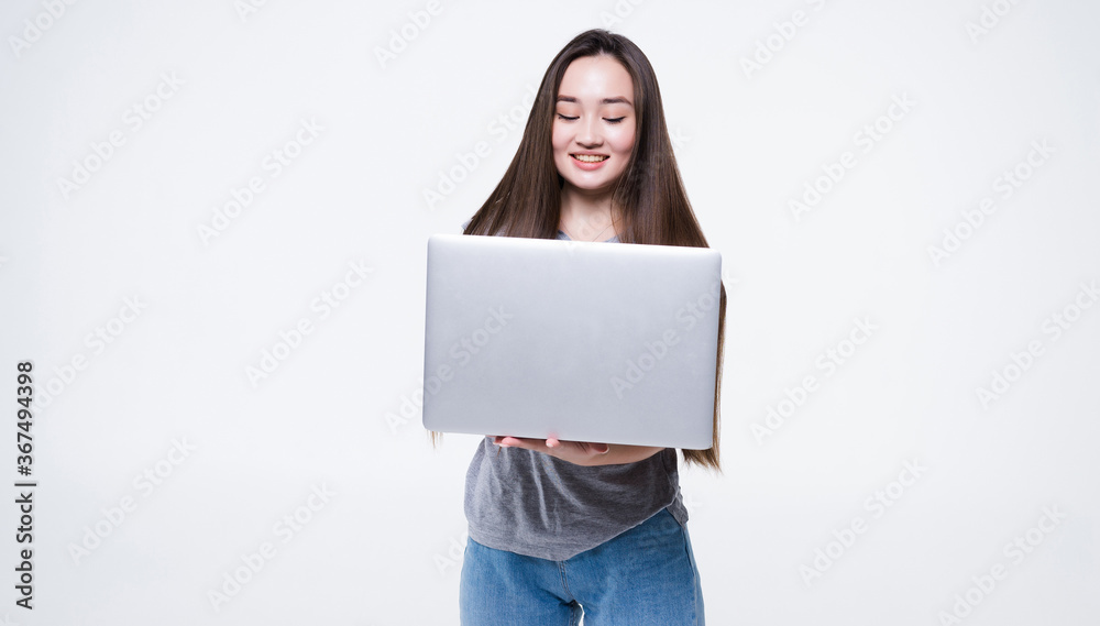 Portrait of a smiling asian woman holding laptop isolated on gray background Portrait of a smiling asian woman holding laptop isolated on gray background