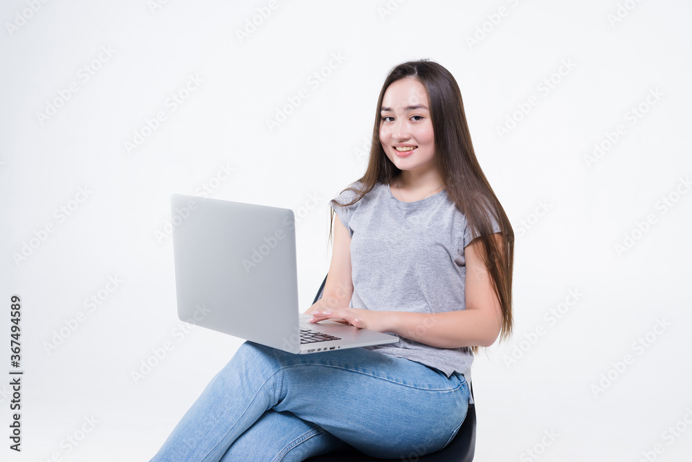 Asian businesswoman talking on the phone and looking at a laptop while sitting on a chair isolated on white background Asian businesswoman talking on the phone and looking at a laptop while sitting on a chair isolated on white background