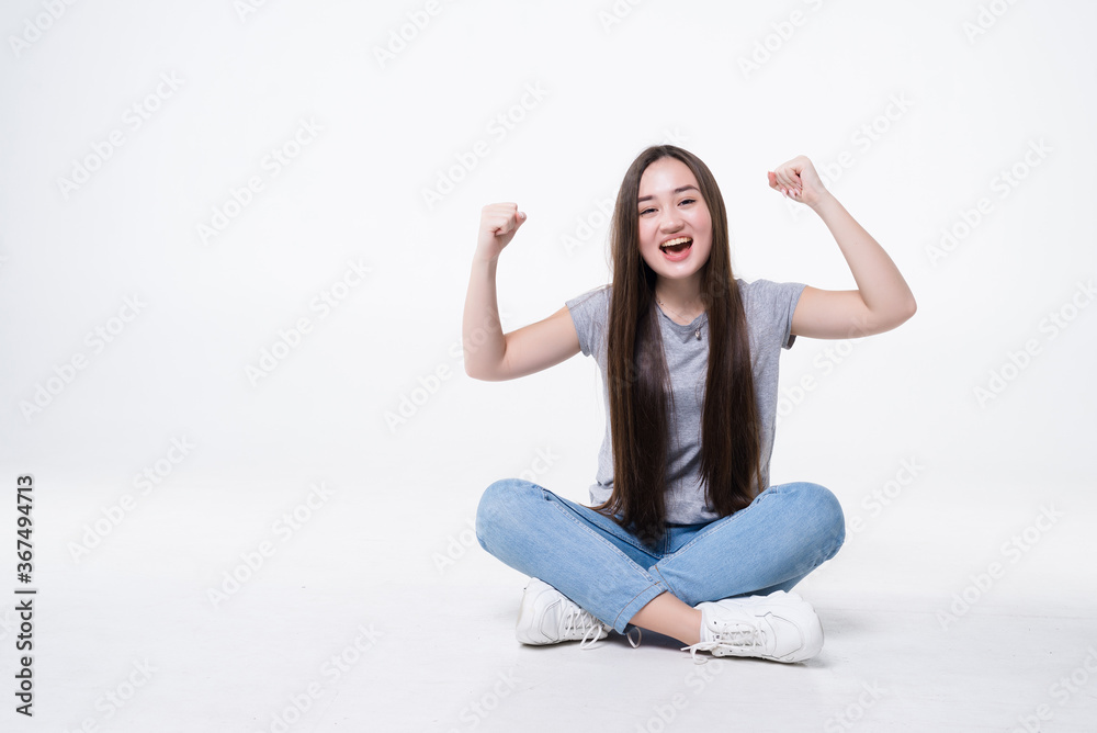 Young pretty woman celebrating success sitting on the floor, isolated on white background Young pretty woman celebrating success sitting on the floor, isolated on white background