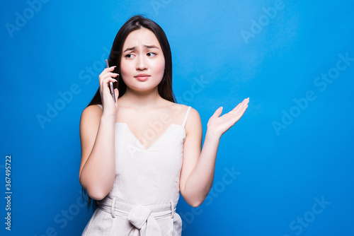 Beautiful young asian woman talking on the telephone on blue background photo