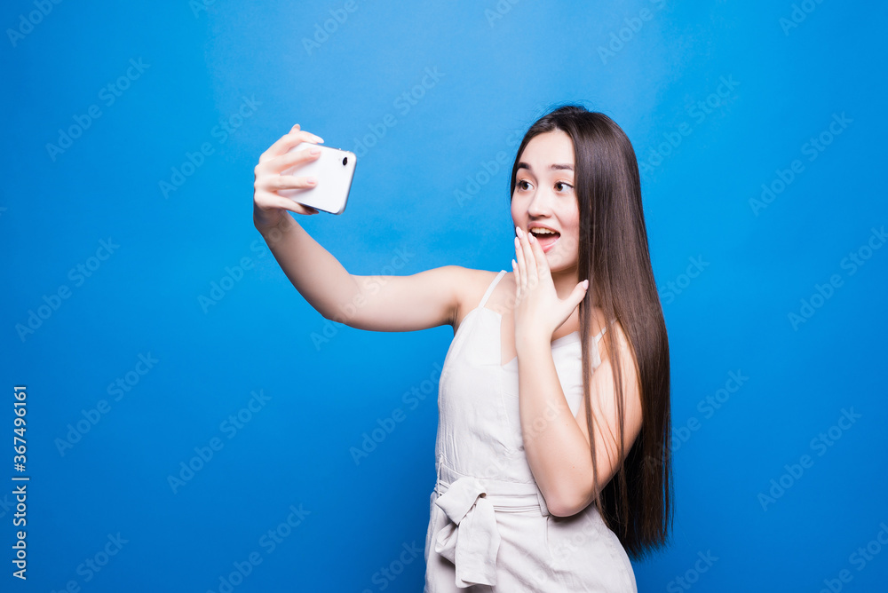 Portrait asian beautiful happy young woman standing smile, holding mobile phone her taking selfie on blue background Portrait asian beautiful happy young woman standing smile, holding mobile phone her taking selfie on blue background