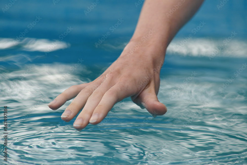 human hand touches the water surface