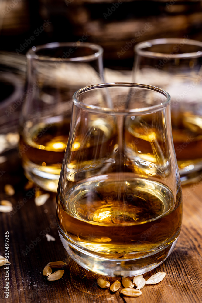 Speyside scotch whisky tasting on old dark wooden vintage table with barley grains Speyside scotch whisky tasting on old dark wooden vintage table with barley grains