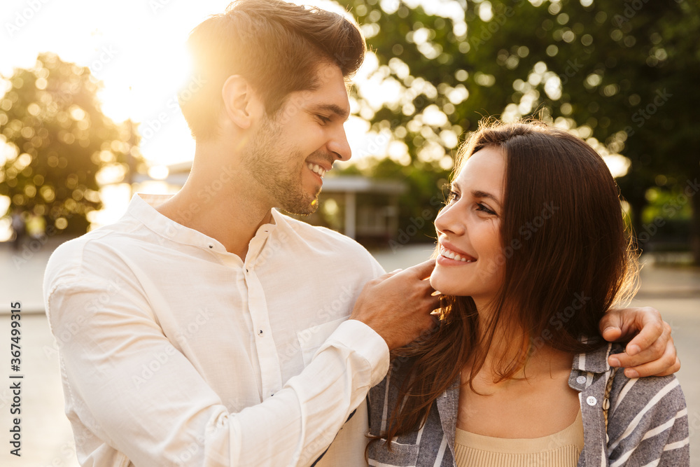 Fototapeta premium Image of young couple smiling while walking through city street