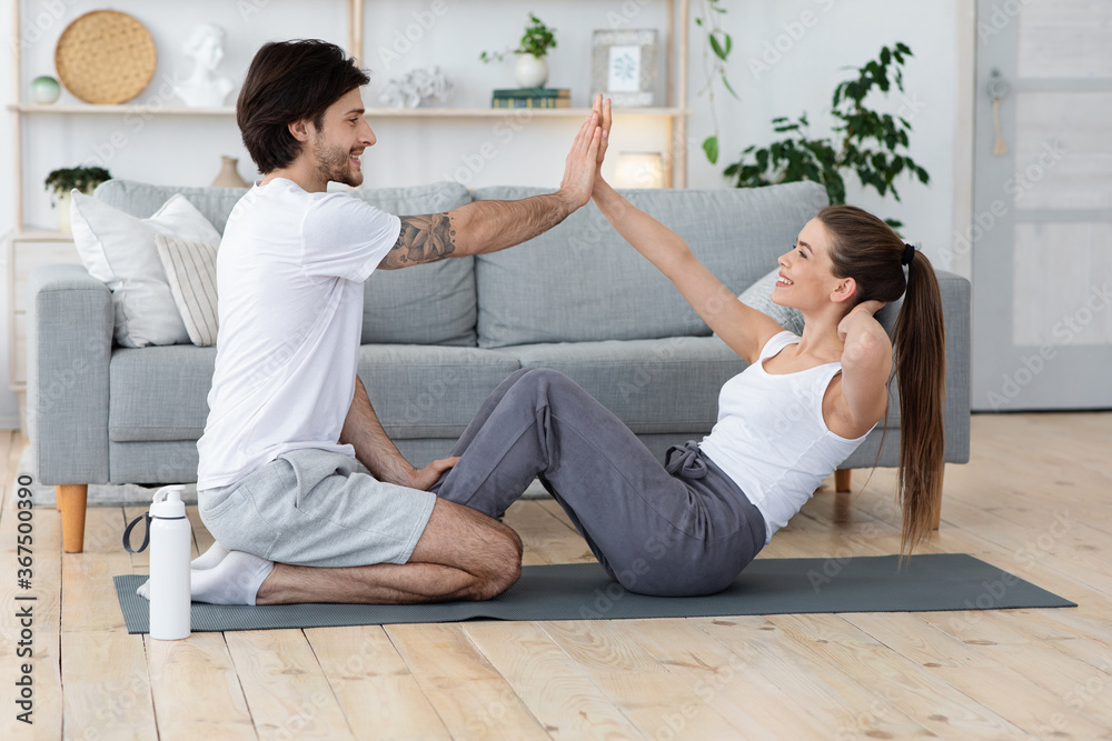 Fototapeta premium Cheerful man and woman training together at living room