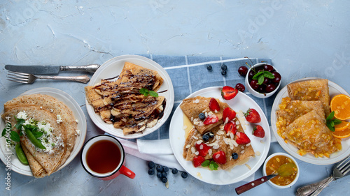 Variety of homemade crepes on grey background.