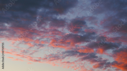Evening sky at sunset. Beautiful natural background or desktop wallpaper. The rays of the setting sun effectively illuminate dark clouds against a light backdrop. Weather forecast