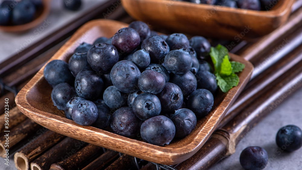 Pile of blueberry fruit in a bowl plate on a tray over gray cement concrete background, close up, healthy eating design concept. Pile of blueberry fruit in a bowl plate on a tray over gray cement concrete background, close up, healthy eating design concept.