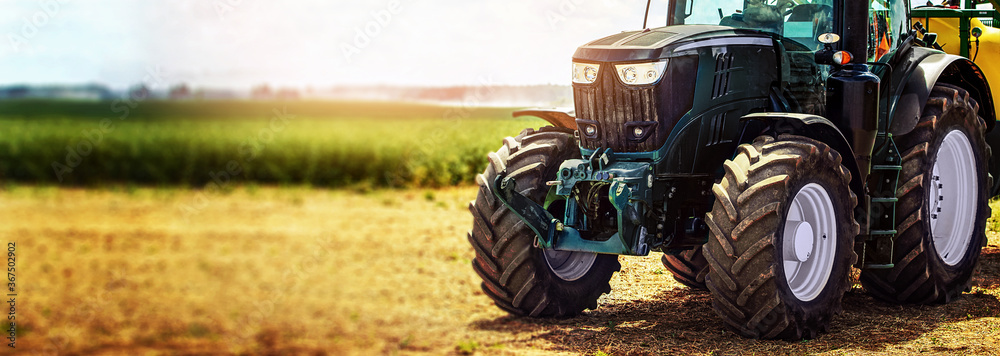 agricultural machinery farm equipment - tractor standing on the field. banner copy space - obrazy, fototapety, plakaty 