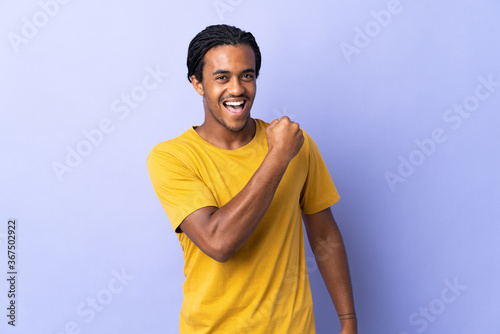 Young African American man with braids man isolated on purple background celebrating a victory