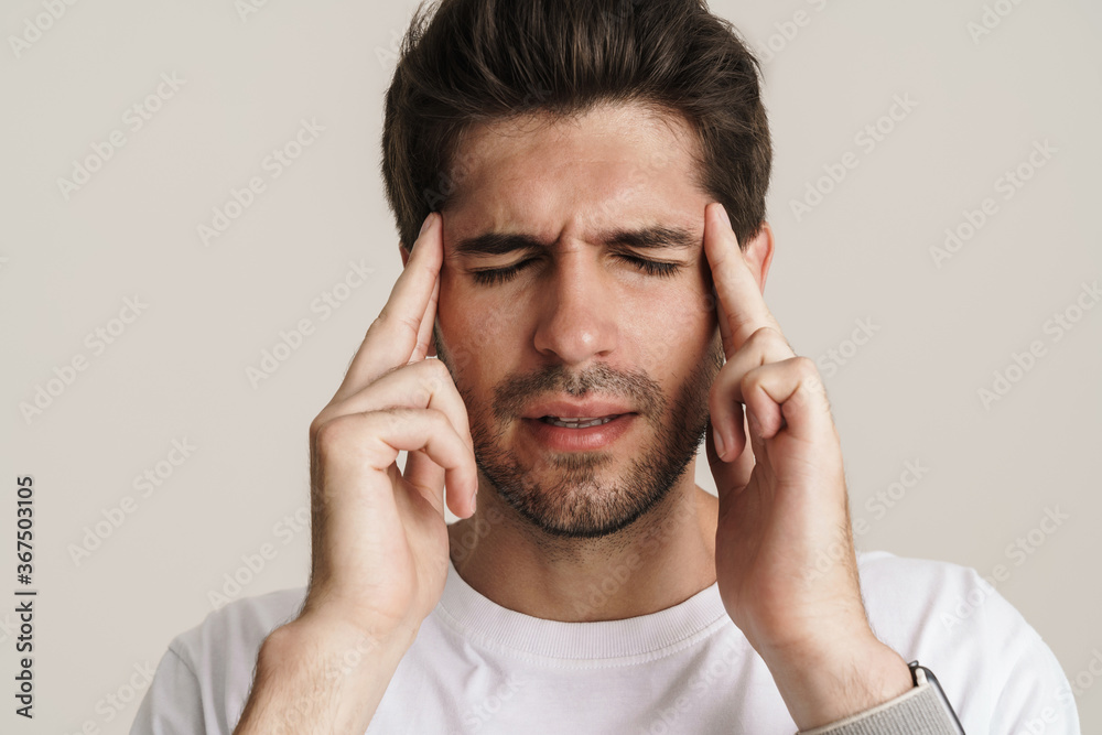 Image of unhappy young man with headache rubbing his temples Image of unhappy young man with headache rubbing his temples