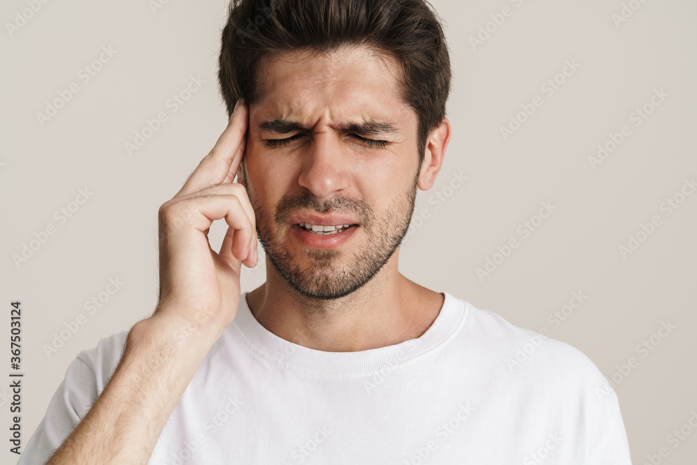 Image of unhappy young man with headache rubbing his temple