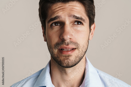 Image of serious businesslike brunette man looking upward and thinking
