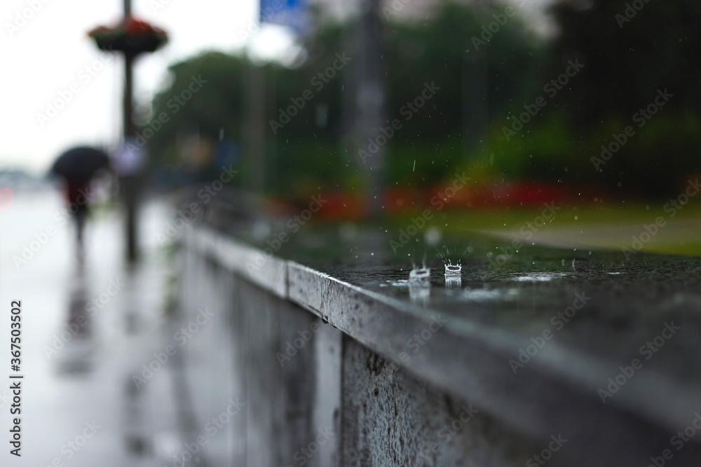 Urban landscape in the rain. Drops on the parapet along the sidewalk