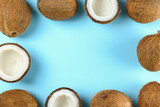 Top view shot of coconuts, whole and cracked on halves on paper textured background with a lot of copy space for text. Background with raw fruit of tropical palm. Flat lay.b