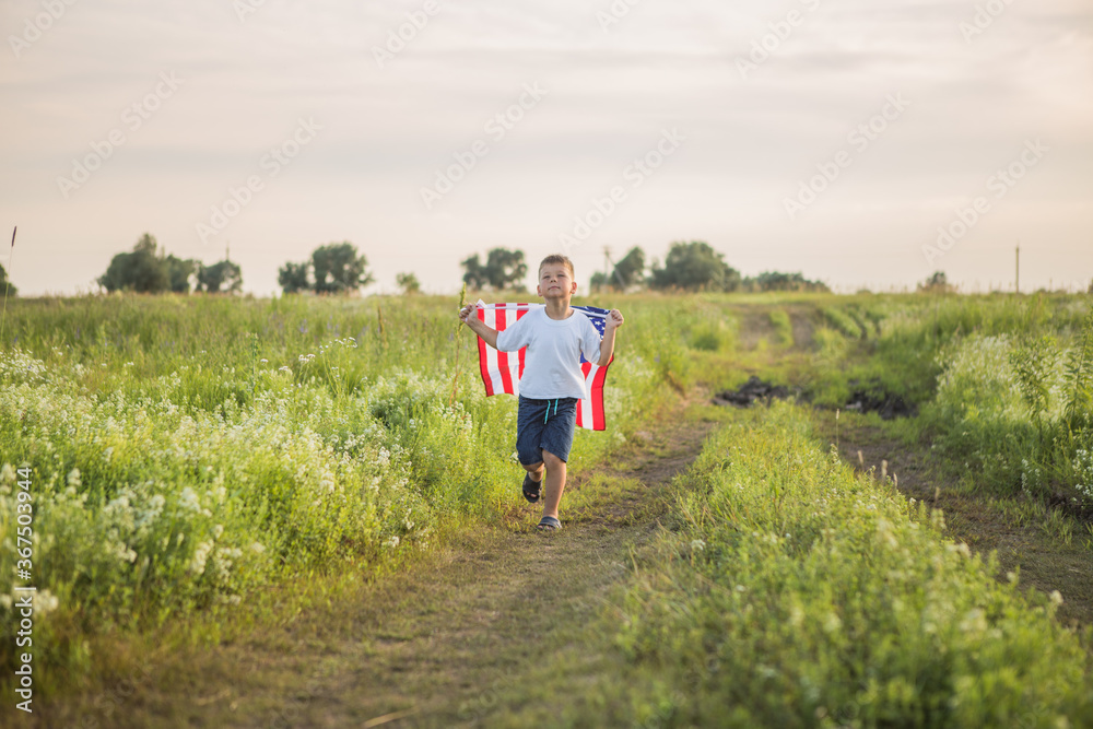 Young boy 4 years old holding an American flag at sunset in field
