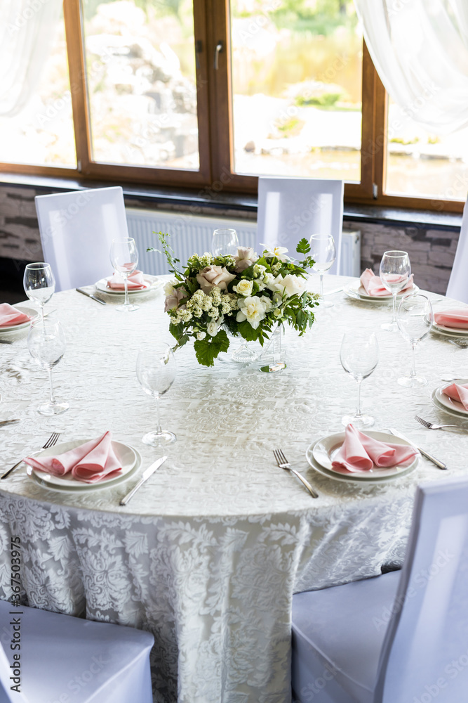 Fototapeta premium Festive table setting with wine glasses, and fresh flowers