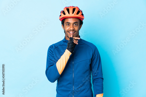 Young cyclist man with braids over isolated background showing a sign of silence gesture putting finger in mouth