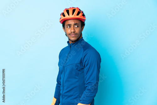 Young cyclist man with braids over isolated background . Portrait photo